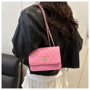 Detail of pink quilted shoulder bag with gold twist lock and chain strap on model