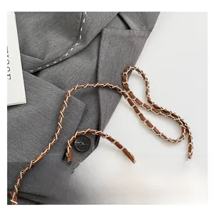 Detail of the elegant gold chain strap with brown leather weaving on a suit