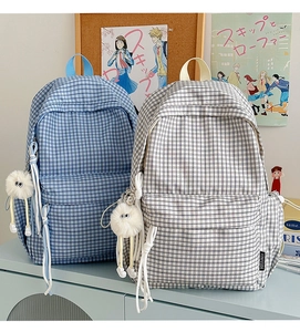 Detail of plaid backpacks with fuzzy charms and woven zippers in a cozy campus setting