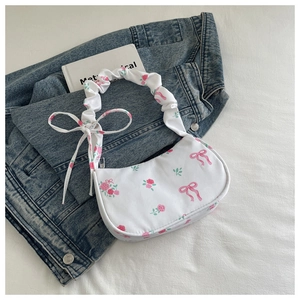Close-up of white shoulder bag featuring pink rose prints and pleated handle details