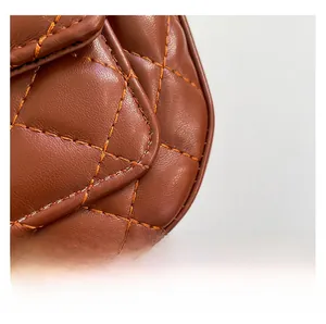 Macro detail of brown quilted leather texture with orange stitching on luxury shoulder bag
