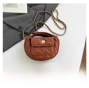 Detail of brown quilted moon bag with floral metal clasp and chain strap on white desk