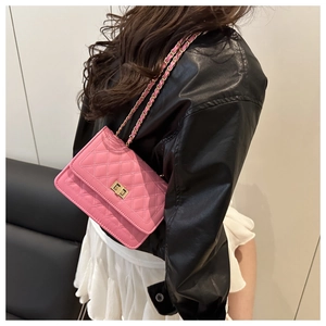 Detail of pink quilted shoulder bag with gold chain strap worn by a model