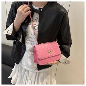 Detail of pink quilted leather crossbody bag with gold metal lock and chain strap