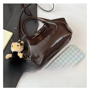 Close-up of a dark brown glossy bucket bag featuring a cute character plush charm