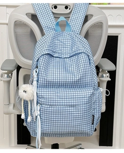 Detailed view of blue and white checkered backpack with a cute white plush charm hanging