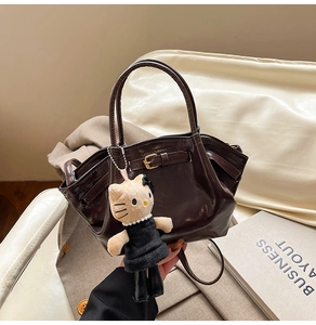 Close-up of chocolate brown leather handbag with vintage metal buckle and plush charm