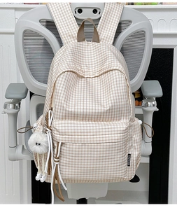 Detail of cream plaid backpack with small check pattern and fluffy white keychain charm