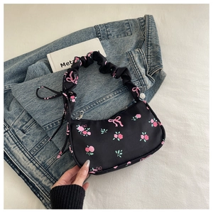 Detailed view of black floral shoulder bag with rose patterns and scrunchie handle