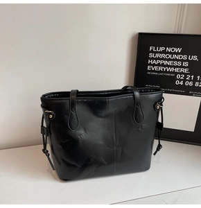 Détail d'un sac cabas en cuir noir brillant avec cordon de serrage et détails dorés
