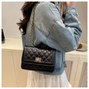Détail du sac bandoulière en cuir noir matelassé avec chaîne dorée et fermoir rotatif