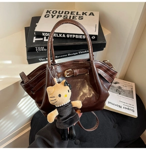 Detail of dark brown faux leather handbag with vintage texture and gold buckle accents