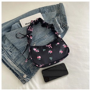 Detail of floral underarm bag with pink rose print and ruffled handle on white fabric