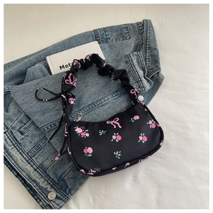 Detail of black floral underarm bag with pink rose patterns and scrunchie strap design