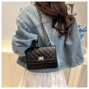 Detail of black quilted leather shoulder bag with gold chain strap and turn-lock closure
