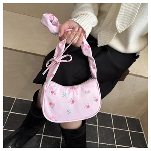 Detail of light pink floral handbag showing rose patterns and soft fabric texture