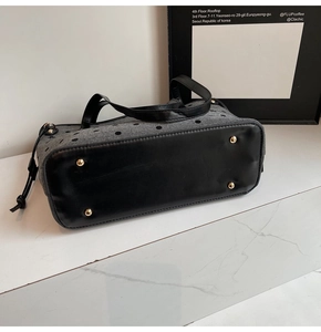 Détail du sac cabas en toile montrant des pois gris et fond noir avec clous en métal