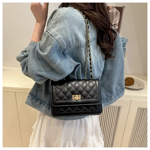 Detail of black quilted leather shoulder bag with gold twist lock and chain strap