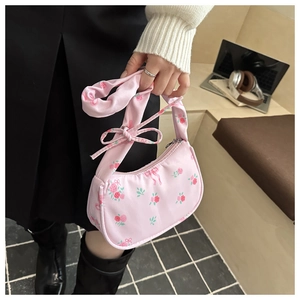 Close-up of pink floral shoulder bag with red patterns and a knotted handle design