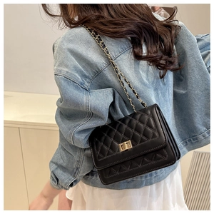 Sac bandoulière matelassé noir avec chaîne dorée porté sur une robe blanche et veste en jean
