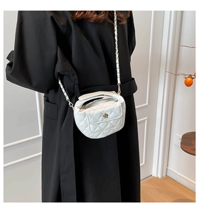 Detail showing the white quilted leather texture and gold flower clasp of the handbag