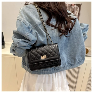 Rear view of a black quilted leather crossbody bag with gold chain strap on a model