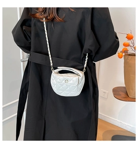 Close-up of white quilted leather crossbody bag with golden chain and floral clasp