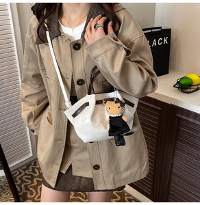 Close-up of beige leather bucket bag with contrast trim and cute kitty plush charm