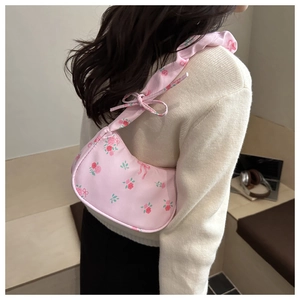 Detailed view of floral shoulder bag with pink roses and ruffled strap bow detail