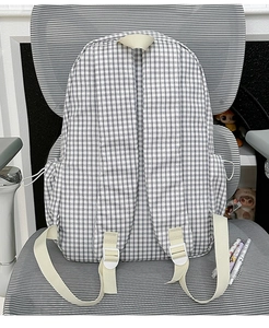 Detail of classic black and white checkered backpack with beige straps on a chair