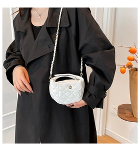 Close-up of white quilted mini bag with floral twist lock and metal chain strap