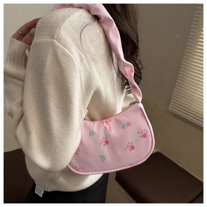 Detail of pink floral shoulder bag featuring rose prints and ribbon patterns on model