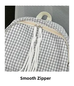 Close-up of smooth double zippers with white cord pullers on plaid backpack
