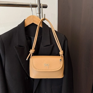 Brown leather underarm bag with silver bow accent over a black blazer background