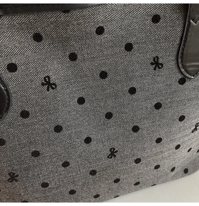 Détail du tissu à chevrons avec pois et poignée en cuir noir sur le sac cabas