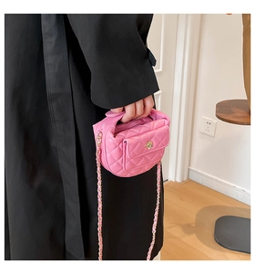 Close-up of pink quilted leather bag with golden flower buckle and chain strap