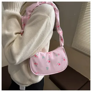 Detail of floral underarm bag with rose pattern and bow design shown on shoulder