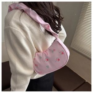 Close-up of pink floral shoulder bag with rose pattern and ruffled strap on a model