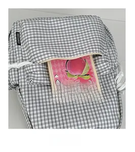 Front zipper pocket detail showing spacious capacity with a notebook inside the plaid backpack