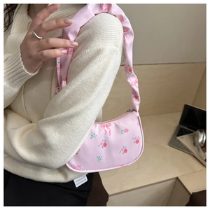 Close-up of pink floral shoulder bag with ribbon prints and ruffled handle strap