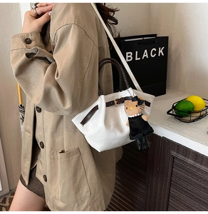 Detail of white pleated bucket bag with brown handle and plush character charm