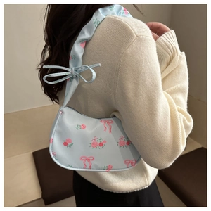 Detailed view of floral underarm bag featuring pink bow accents and shoulder strap knots