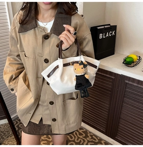 White faux leather handbag with brown handles and a cute plush cat doll keychain