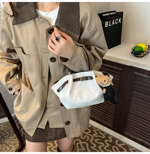 Close-up of a white cloud-shaped handbag with brown strap and cute cat plush pendant