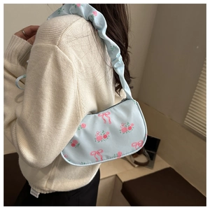 Close-up of floral light blue underarm bag with pink roses and bow prints and pleated strap