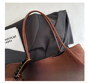 Detailed top view of a brown suede tote bag with decorative abacus keychain and grey blazer