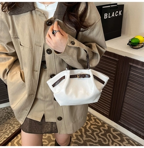 Detail of white glossy cloud bag with pleated design and dark brown buckle strap