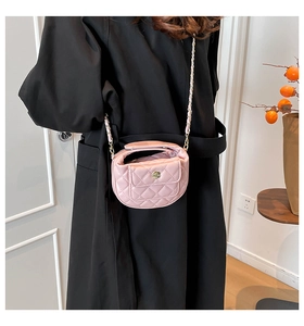 Detail of pink quilted crossbody bag with gold camellia buckle and chain strap