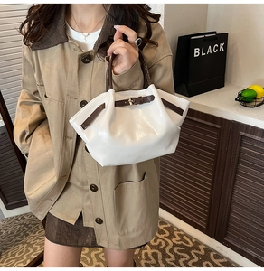 Detail of cream pleated handbag with brown straps and golden buckle in lifestyle setting