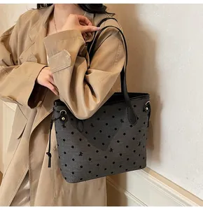 Grand sac cabas gris à pois noirs et nœuds porté sur un trench-coat élégant beige